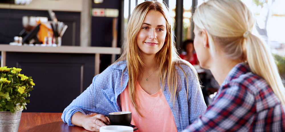 Two women sat inside with coffees.
